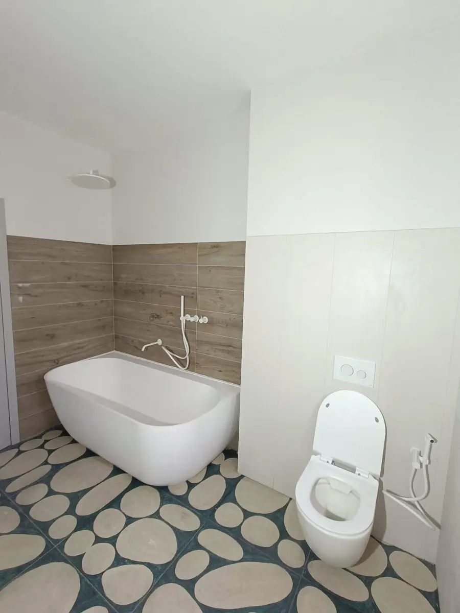 Baie cu cadă freestanding și vas de WC suspendat, cu toate instalațiile sanitare finalizate