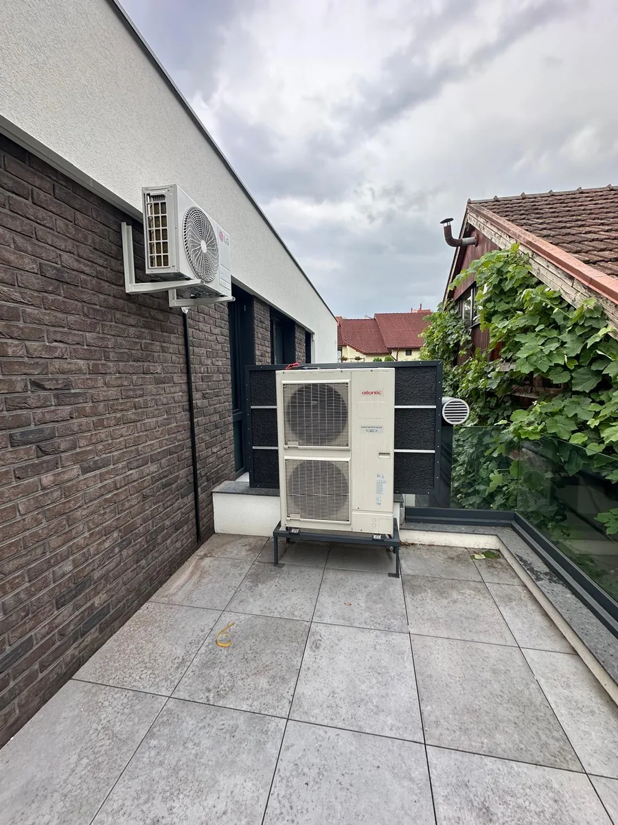 Unitate exterioară de pompă de căldură montată pe terasă, lângă unitatea de climatizare de pe fațadă